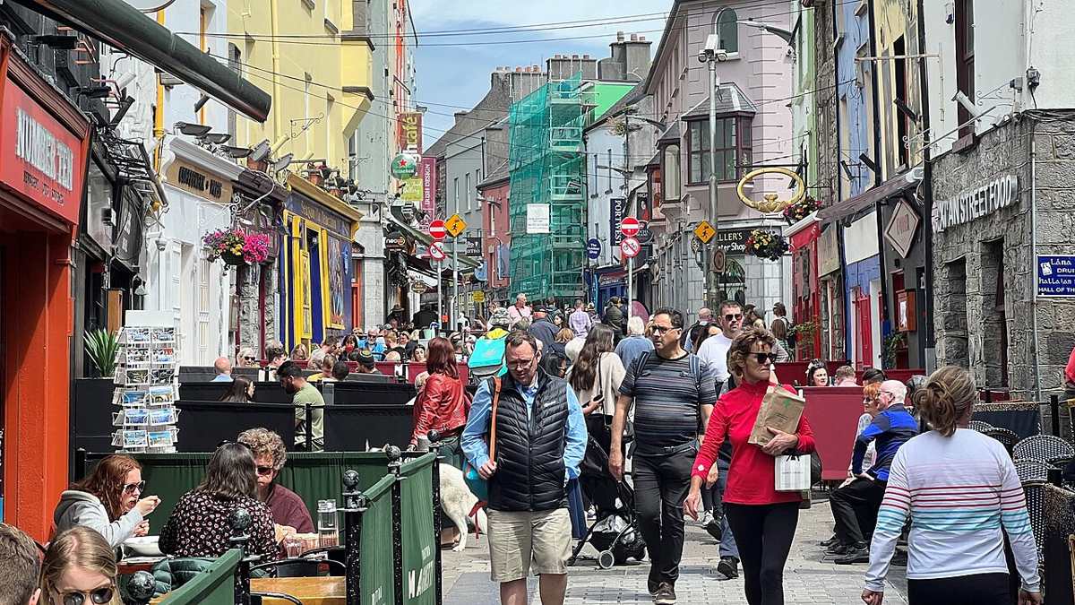 Pedestrians and colourful shopfronts on Quay Street in June 2022