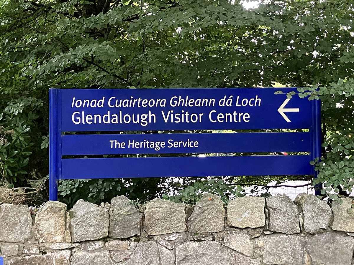 A blue sign directing visitors to Glendalough Visitor Centre