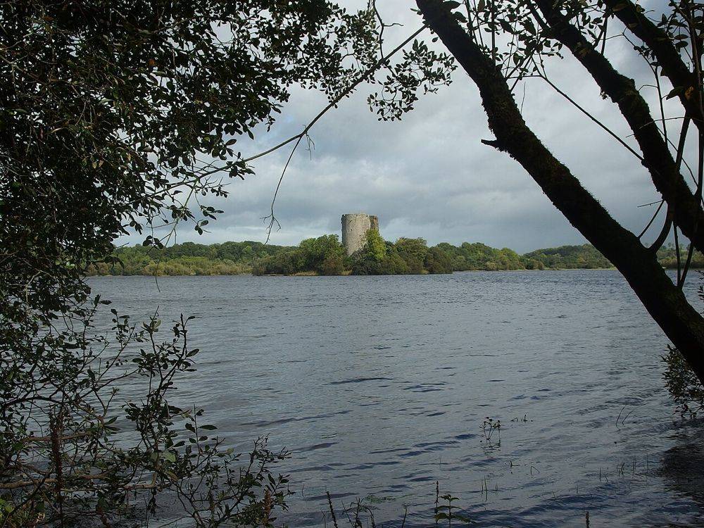 Clough Oughter Castle on its lake island, seen from a wooded shore