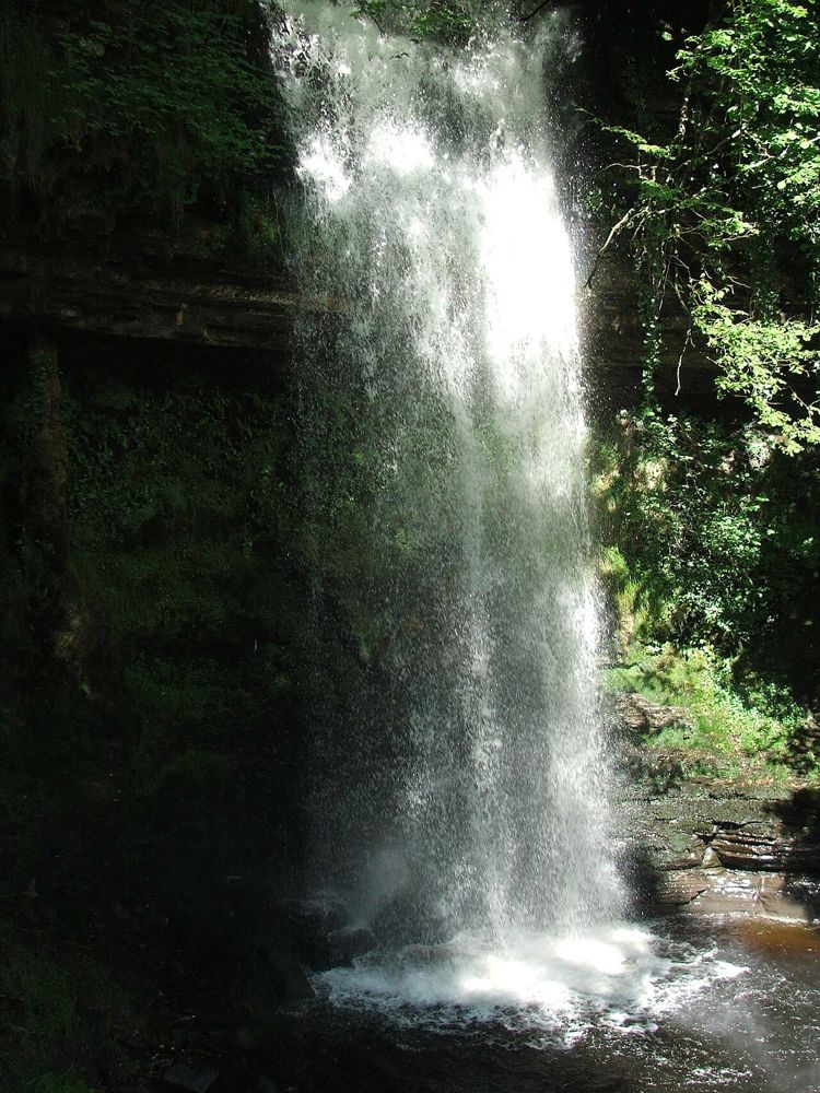 Glencar Waterfall descending between dark rocks and woodland